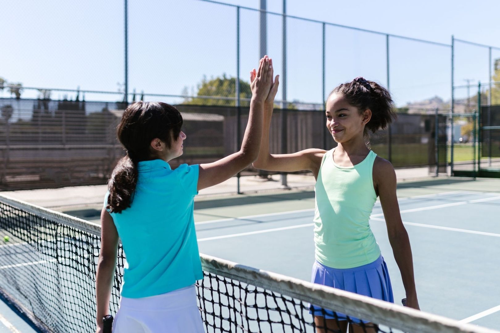 Två tennisspelare gör high five vid nätet på en utomhusbana