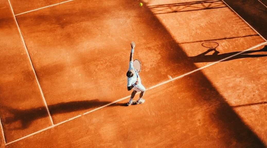 Tennisspelare förbereder en serve på en solbelyst grusbana